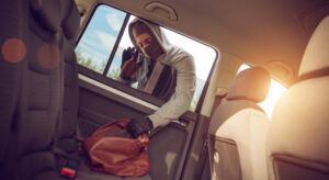Man stealing bag out of car that from someone that does not know how to prevent car theft