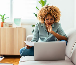 Young woman sitting indian style on sofa looking at a laptop